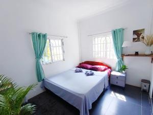 a bedroom with a bed and two windows at Sam's Guesthouse M'Pai Bay in Koh Rong Sanloem