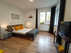 una camera da letto con un letto con cuscini arancioni e una TV di PIF Apartments Sadoveanu a Braşov