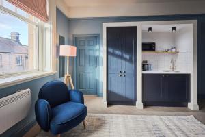 een woonkamer met een blauwe stoel en een wastafel bij Arlington House Hotel - Luxurious Self Check-In Ensuite Rooms in the Centre of Wooler in Wooler