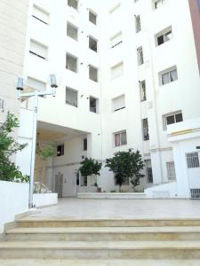a large white building with stairs in front of it at JARDIN Apartments in El Aouina