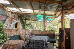 a covered porch with a couch and a table at Earthship amazing Cabins with lake view in San Marcos La Laguna