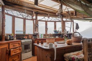 a kitchen with a table and a stove and some windows at Earthship amazing Cabins with lake view in San Marcos La Laguna