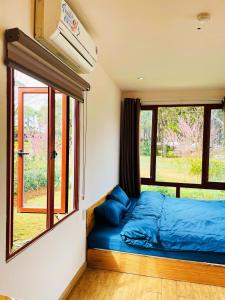 a bedroom with a blue bed in front of a window at Homestay Gió Mộc in Mộc Châu