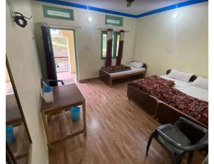 Habitación con 2 camas y mesa. en Anoop Tourist Guest House, Phata en Phata