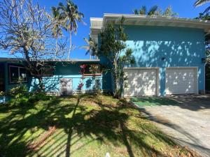 a blue house with a white garage at Tranquil Beachfront Duplex-type Private House! in Hauula