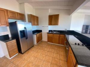 cocina con armarios de madera y nevera de acero inoxidable en Tranquil Beachfront Duplex-type Private House!, en Hauula