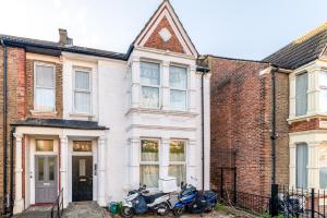 two motorcycles parked in front of a white house at LiveStay - Modern Apartments on Acton Lane in London