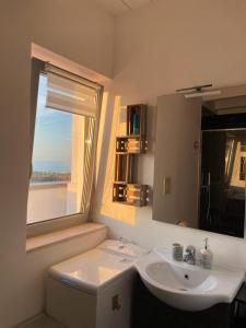 baño blanco con lavabo y ventana en Attico - Il Panorama, en Barletta