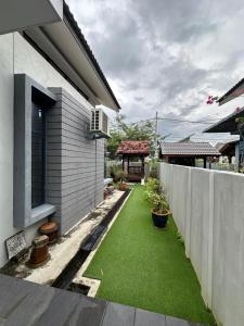 a small backyard with green grass next to a house at Dhuha Homestay in Kampong Kerubong