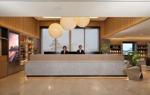 two women standing at a reception desk in a lobby at Intercity Yangzhou Slender West Lake in Yangzhou