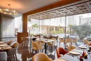 a restaurant with tables and chairs and a large window at The Biltmore Hotel Villas Dubai in Dubai