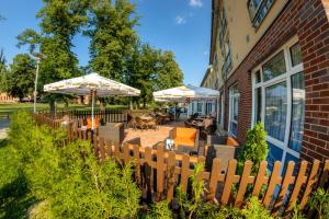 ein Holzzaun mit Sonnenschirmen, Tischen und Stühlen in der Unterkunft Hotel & Restaurant am Schlosspark in Dahme