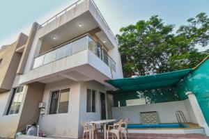 a house with a balcony and a table and chairs at EMPYREAN STAY ll 2BHK ll PRIVATE POOL ll GOOD LUCK VILLA ll FREE BREAKFAST in Lonavala