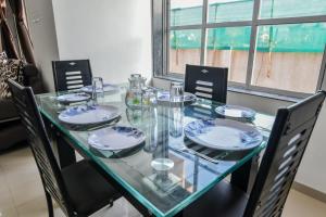 a glass table with chairs and plates on it at ll 2BHK ll PRIVATE POOL ll GOOD LUCK VILLA ll FREE BREAKFAST in Lonavala