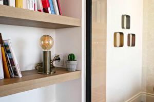 a book shelf with a lamp and a cactus on it at BEACHVIEW KEYWEEK Beachfront Renovated Apartment with Parking in Biarritz in Biarritz +11 photos