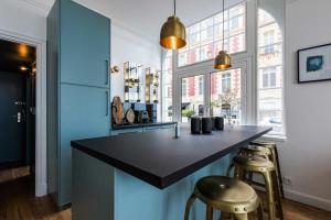 a kitchen with a black counter and two stools at BLUE MOON KEYWEEK Seafront Apt with large Terrace and Parking Biarritz in Biarritz
