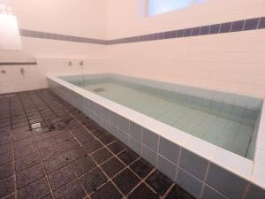 a bath tub in a room with a tile floor at KANEKAKU in Hakuba