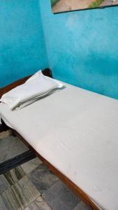 Cama blanca en habitación con pared azul en Khaja Hotel en Calcuta