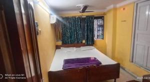 Cama pequeña en habitación con ventana en Khaja Hotel, en Calcuta