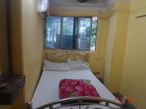 a small bedroom with a bed with a window at Khaja Hotel in Kolkata