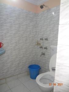 a bathroom with a toilet and a blue bucket at Khaja Hotel in Kolkata