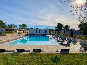 a swimming pool with lounge chairs and a building at Mobile Home Aura, Village Twins in Pakoštane