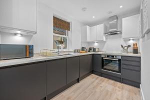 una cocina con armarios grises y electrodomésticos blancos en 1 BR, central Southampton, Stunning Apt by Blue Puffin Stays, en Southampton