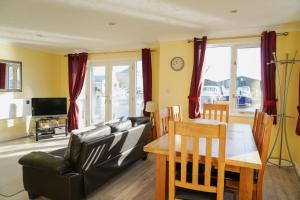 een woonkamer met een zwarte leren bank en een tafel bij Swift Cottage, Norfolk Broads in Potter Heigham