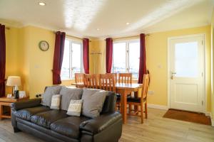 een woonkamer met een leren bank en een tafel bij Swift Cottage, Norfolk Broads in Potter Heigham