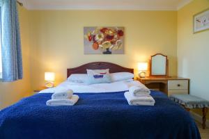 een slaapkamer met een blauw bed met handdoeken erop bij Swift Cottage, Norfolk Broads in Potter Heigham