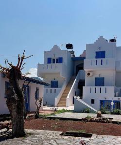 a group of white buildings with blue doors and a tree at Sissi Holiday Appartement in Sisi