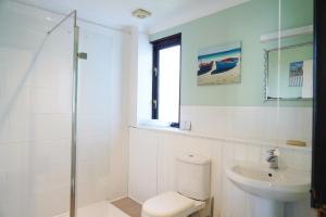 een witte badkamer met een toilet en een wastafel bij Swift Cottage, Norfolk Broads in Potter Heigham +13 foto's