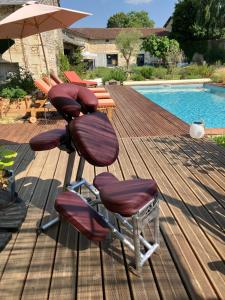 two chairs and an umbrella on a deck next to a pool at Le Manoir des Sables - Chambre familiale grand confort in Berthegon