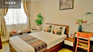 een slaapkamer met een bed, een tafel en een stoel bij HANZ The Galaxy Hotel in Ho Chi Minh-stad
