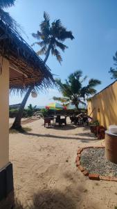 Tripsea Beach Villa في أليبي: منطقة نزهة مع طاولات والنخيل على الشاطئ