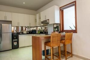 a kitchen with white cabinets and a table and chairs at Villa Orange Seminyak in Seminyak