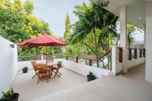 a patio with a table and chairs and an umbrella at Villa Orange Seminyak in Seminyak