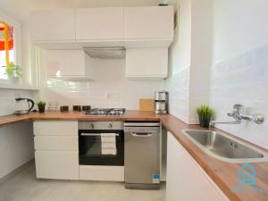 Wave Apartment في غدانسك: مطبخ مع دواليب بيضاء ومغسلة
