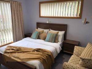 a bedroom with a large bed and a chair at Sunshine Apartment in Austins Ferry
