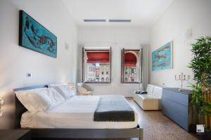 a white bedroom with a bed and a couch at Urbanicooh Paracelso - Piazza Maggiore View in Bologna