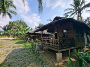 a small hut with a thatched roof and palm trees at California Breeze Campsite in Indang