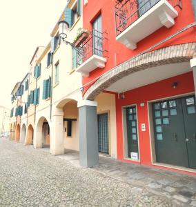 Domus Padova Centro Storico في بادوفا: مبنى احمر وبيض على شارع مرصوف بالحصى