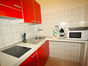 a kitchen with red cabinets and a sink and a microwave at Domus Padova Centro Storico in Padova