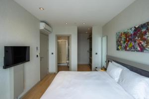 a bedroom with a white bed and a flat screen tv at Fraser Place Antasya Istanbul in Istanbul