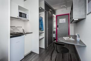 eine kleine Küche mit einem Tisch und einem schwarzen Stuhl in der Unterkunft Cabinn Plus Esbjerg in Esbjerg