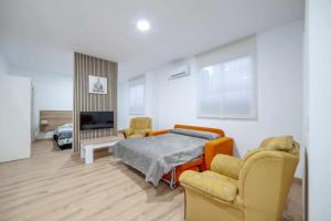 1 dormitorio con 1 cama, 2 sillas y TV en Apartamentos Avd Xerez, en Sevilla