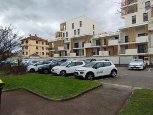 eine Reihe von Autos, die auf einem Parkplatz vor einem Gebäude geparkt sind in der Unterkunft Logement spacieux rénové, calme et proche du métro in Villeurbanne