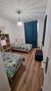 1 dormitorio con 2 camas y cortina azul en Logement spacieux rénové, calme et proche du métro en Villeurbanne