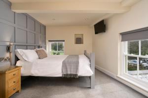 a bedroom with a bed and a tv and a window at Church House Inn, Stokenham in Kingsbridge