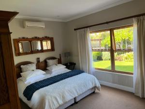 a bedroom with a bed and a large window at La Pension Guest House in Oudtshoorn